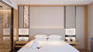 A hotel room with a large bed, bedside tables, a desk, and a glass shower enclosure. - Courtyard by Marriott Hangzhou West (Hangzhou)