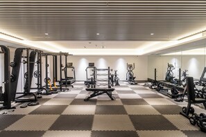 A gym with various exercise equipment, a mirrored wall, and a checkered floor. - Courtyard by Marriott Hangzhou West (Hangzhou)
