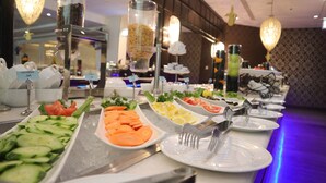 Un bufé con diversos alimentos, incluyendo pepinos, tomates y rodajas de limón.