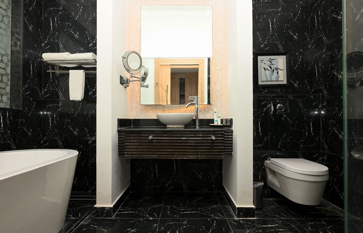 A modern bathroom with a freestanding bathtub, a vanity with a sink and mirror, and a toilet.