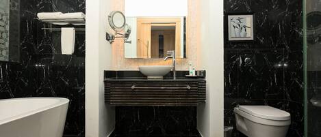 A modern bathroom with a freestanding bathtub, a vanity with a sink and mirror, and a toilet.