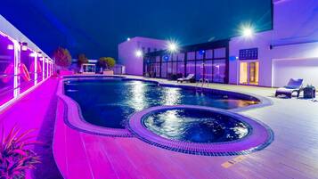 Una piscina al aire libre, sillones reclinables de piscina