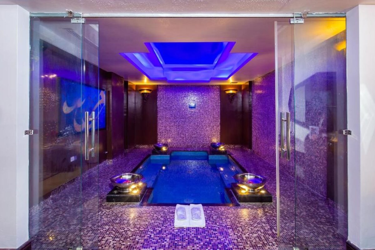 A spa room with a glass-enclosed pool, a ceiling light fixture, and a tiled floor.