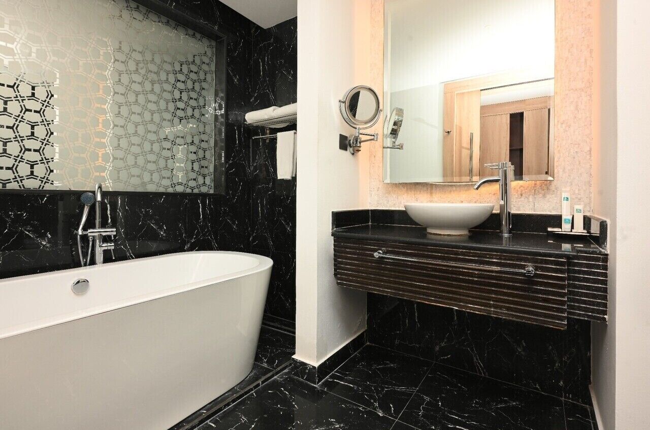 A modern bathroom with a freestanding bathtub, a round mirror, and a sink with a marble countertop.