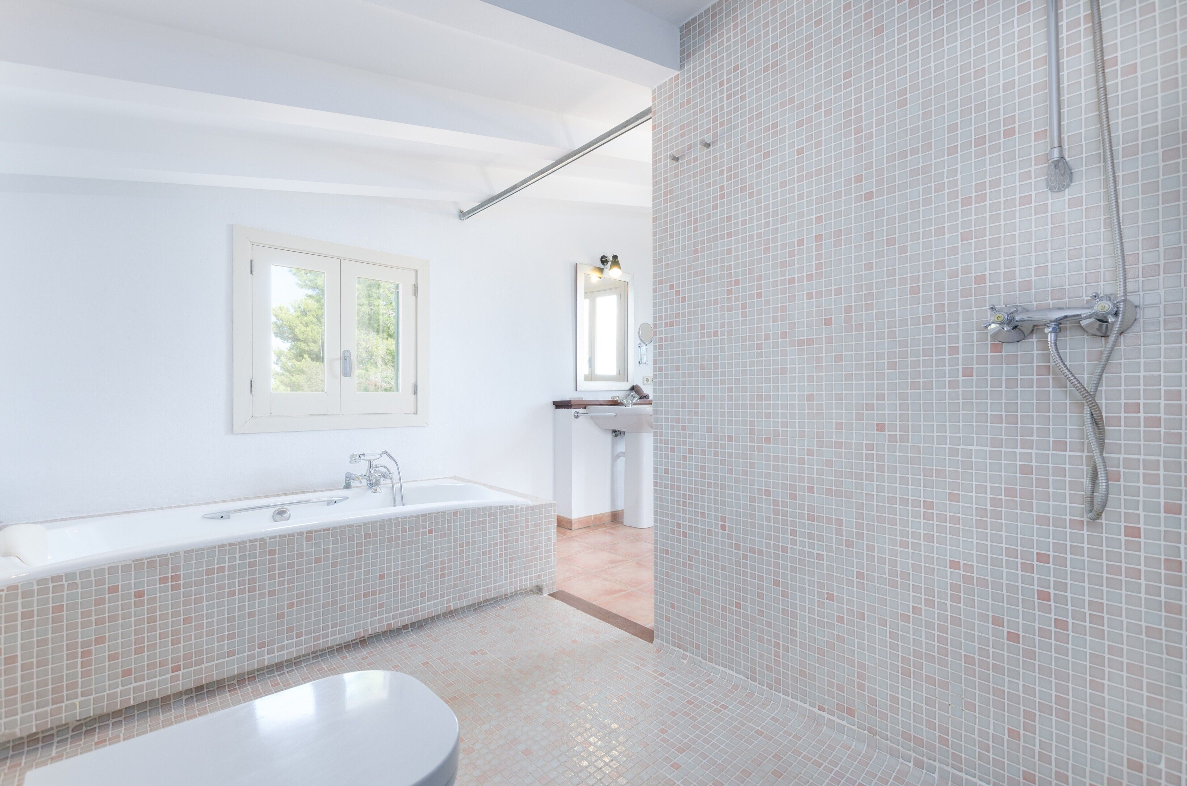 A modern bathroom with a large bathtub, a shower area, and a sink.
