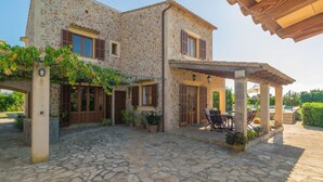 Un edificio de piedra con un patio cubierto, mobiliario exterior y plantas en macetas.