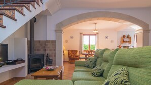 Una sala de estar con un sofá verde, una chimenea, una mesa de madera y una escalera.