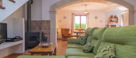 A living room with a green sofa, a fireplace, a wooden table, and a staircase.