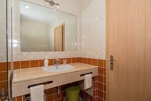 Une salle de bain avec un lavabo, un miroir et une porte.