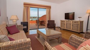 Sala de estar con sofá, sillones, una mesa de centro, televisor y un balcón con vistas.