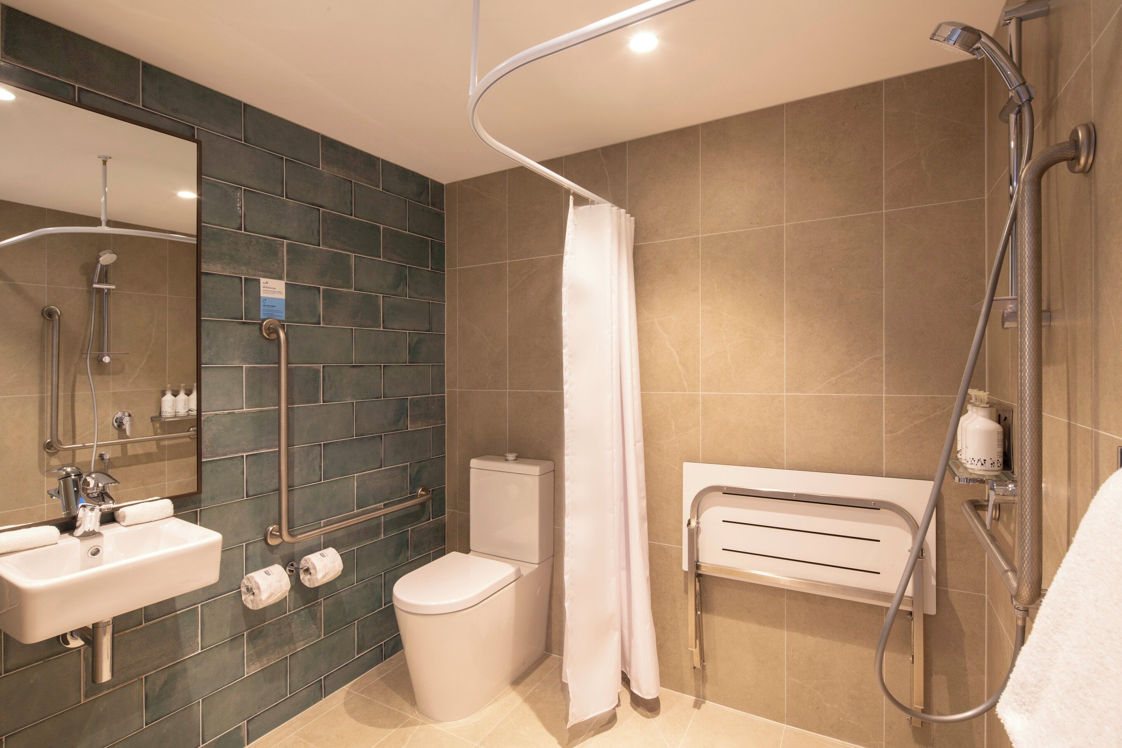 Un baño moderno con ducha, inodoro, lavabo y barandilla.