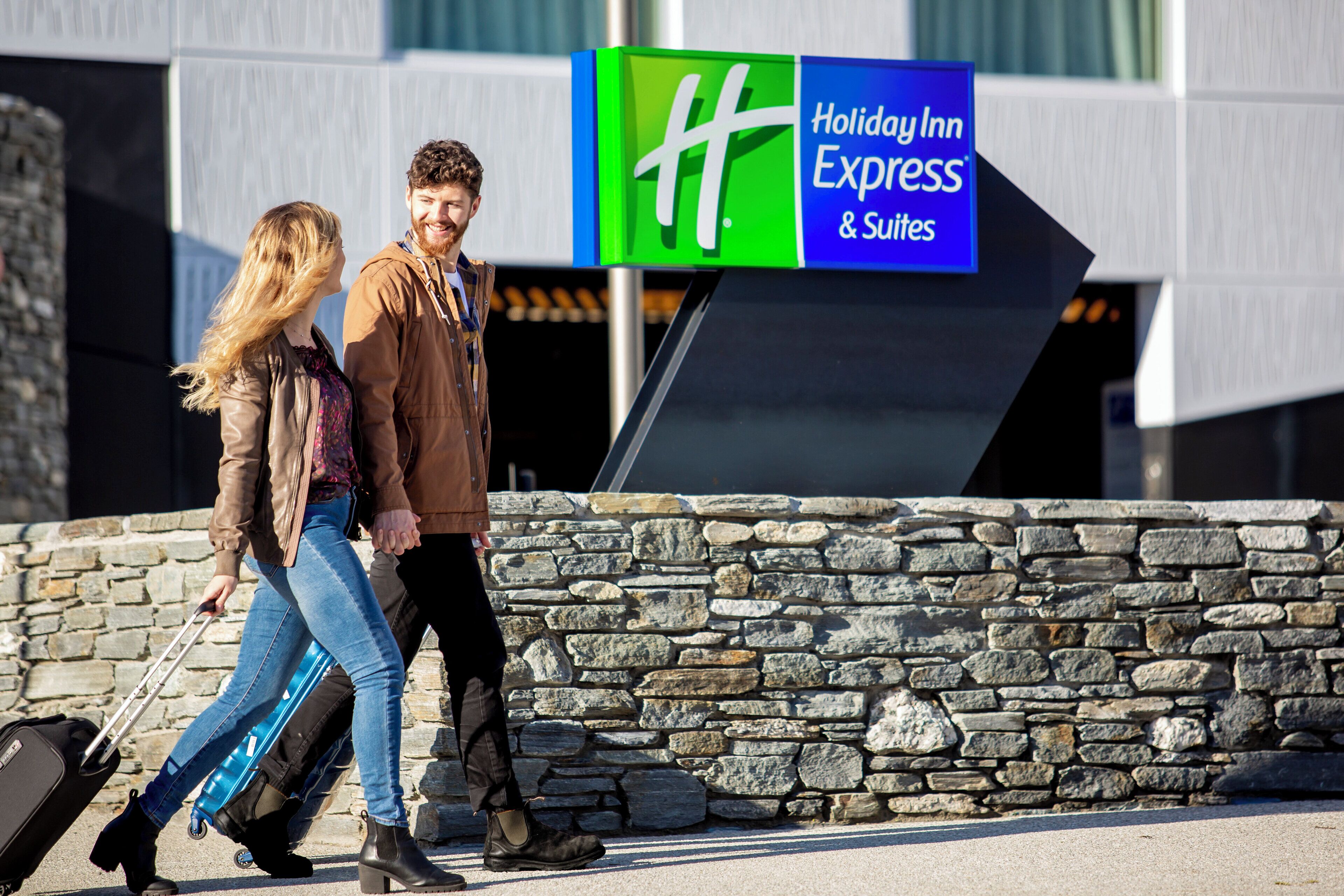 Un couple passe devant une enseigne d’un hôtel Holiday Inn Express.