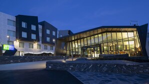 A modern hotel with a glass facade, stone steps, and a sign for the Holiday Inn Express. - voco Queenstown by IHG (Queenstown)