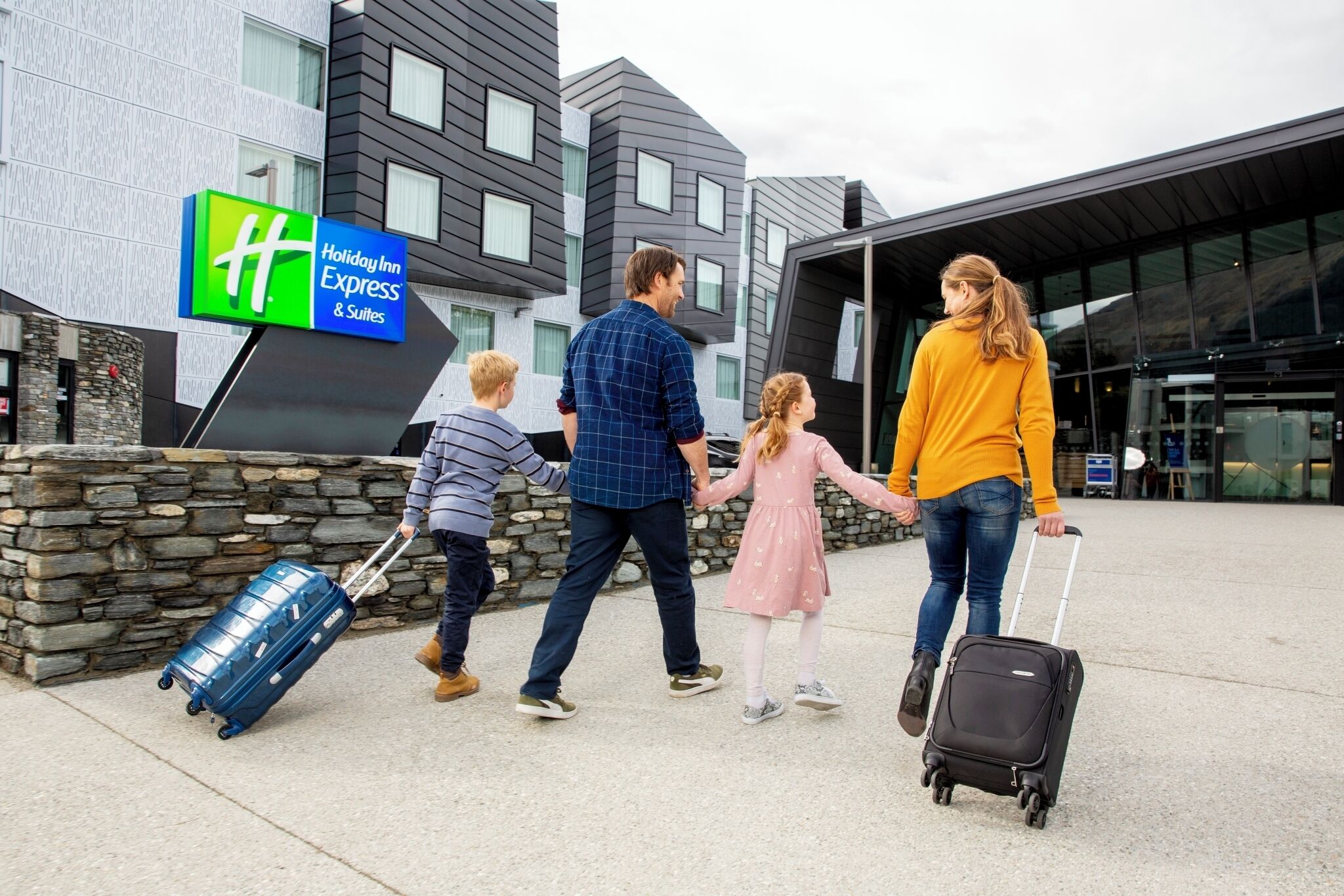 Una familia caminando hacia un edificio Holiday Inn Express & Suites.