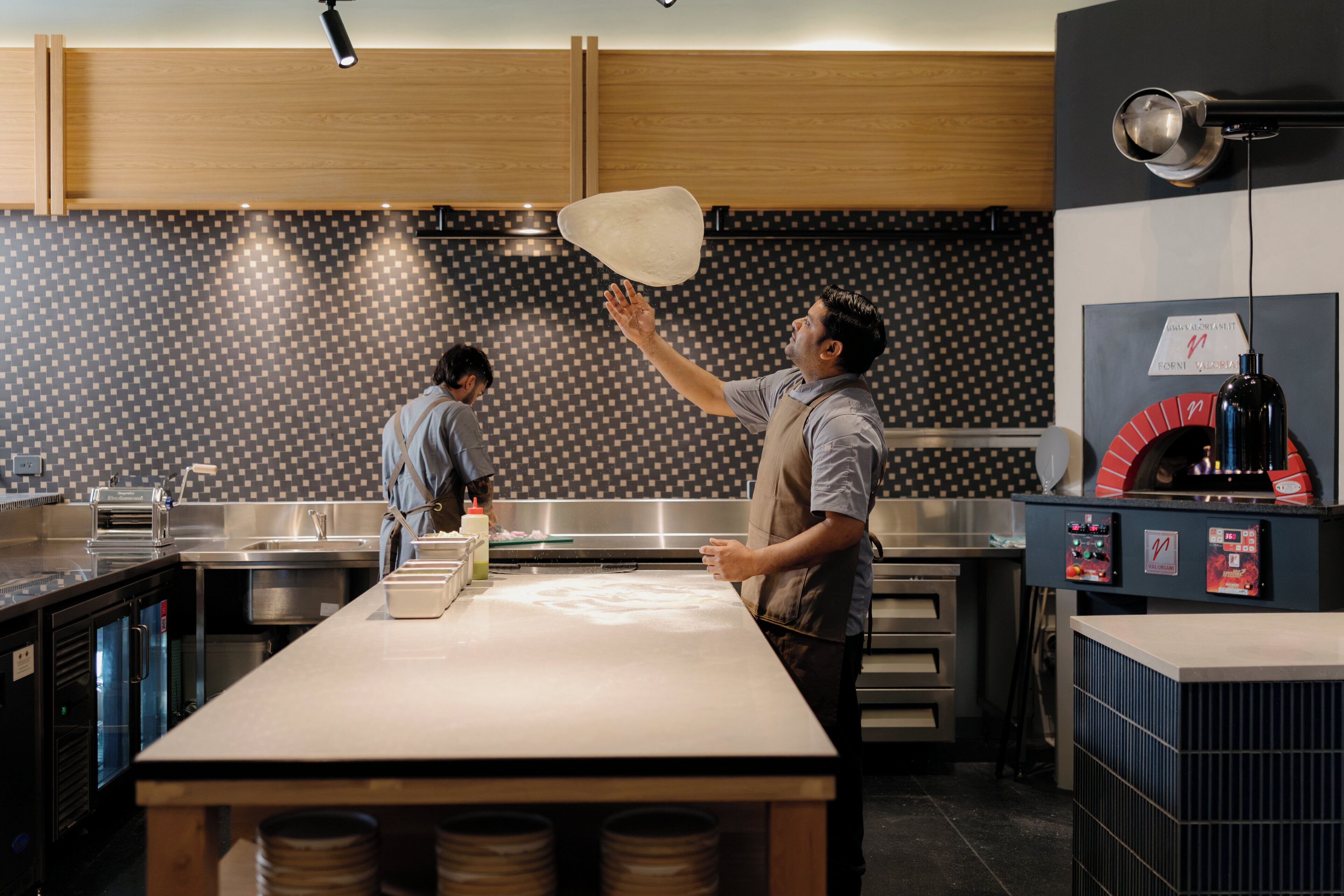 A modern kitchen with a large island, stainless steel appliances, and a patterned backsplash.