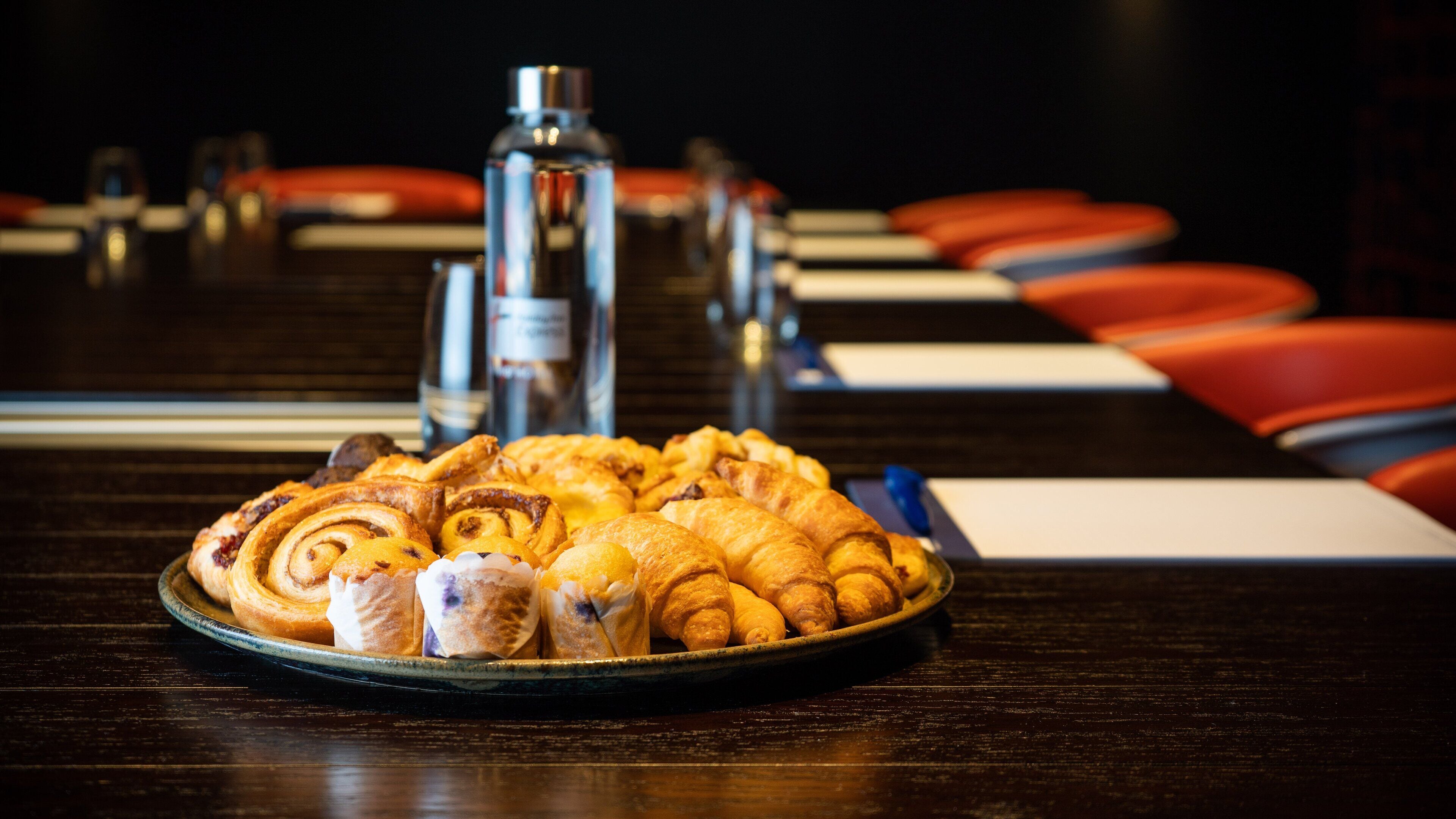 A table with a plate of pastries and a bottle of water.