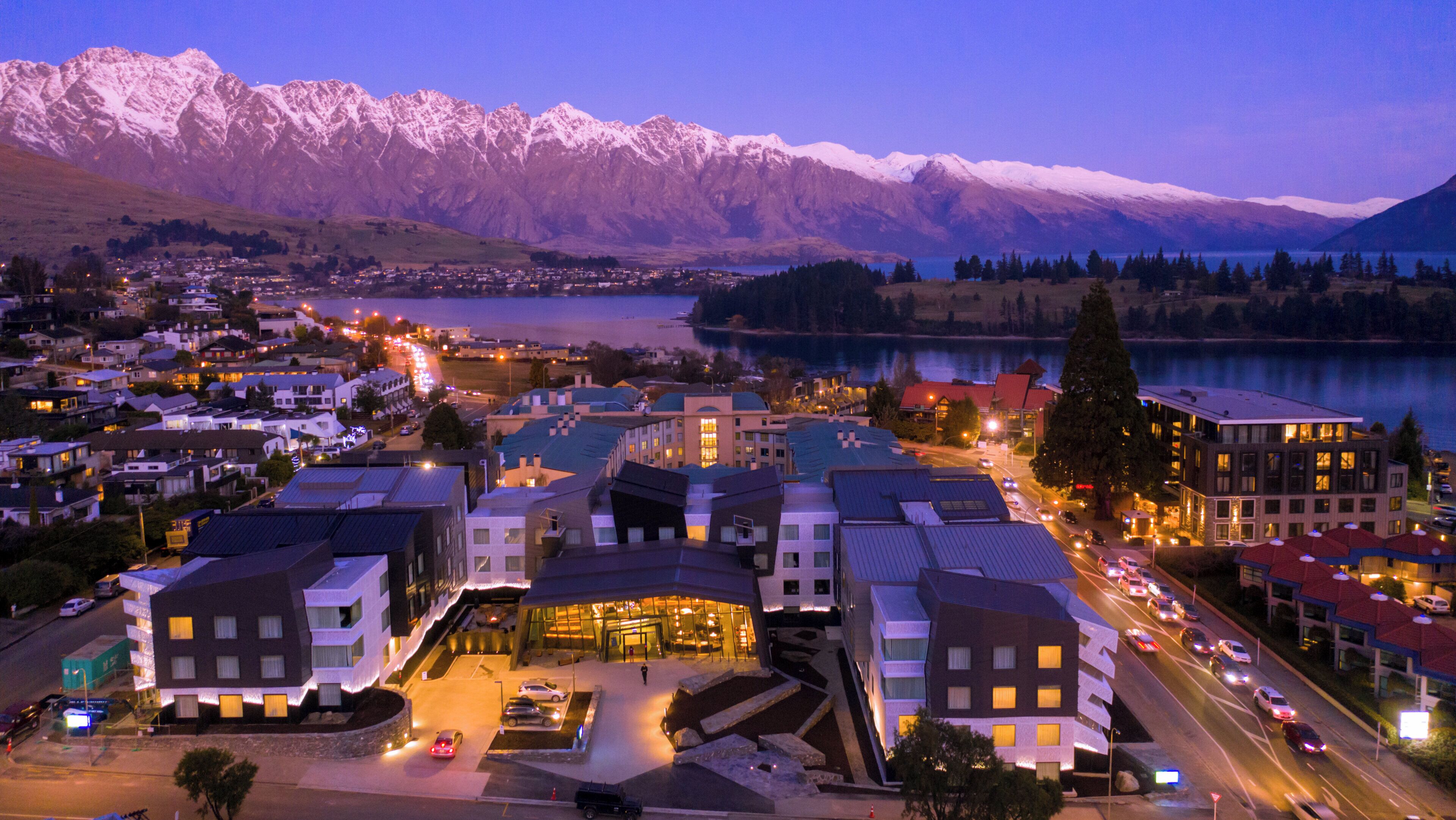 A town with a lake, mountains, and a mix of modern and traditional buildings.