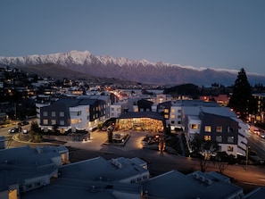 A modern hotel with a central courtyard, surrounded by residential buildings, with a mountain range in the background. - voco Queenstown by IHG (Queenstown)