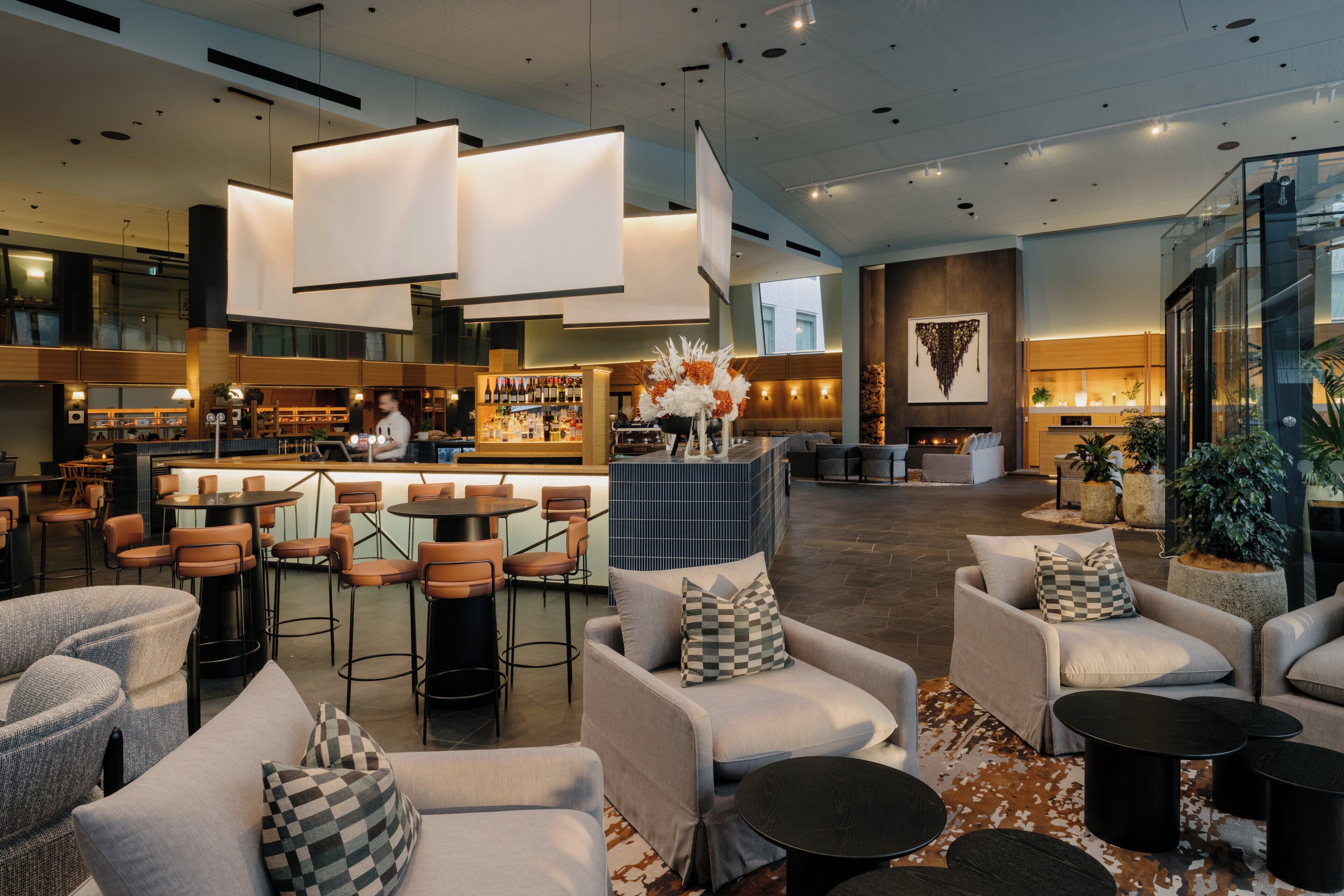 A modern bar area with seating and a bartender.