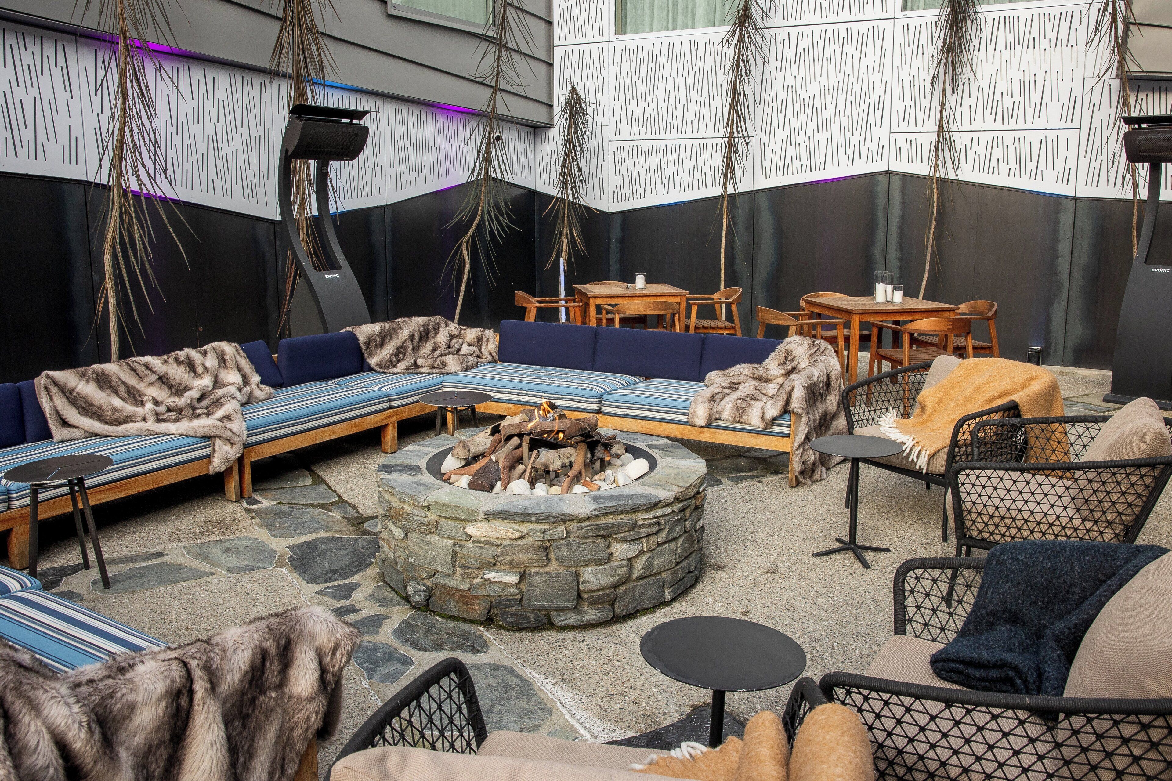 Un espacio al aire libre acogedor con una chimenea de piedra, sofás y sillones.