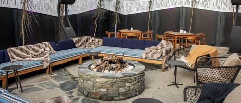 Un espacio al aire libre acogedor con una chimenea de piedra, sofás y sillones.