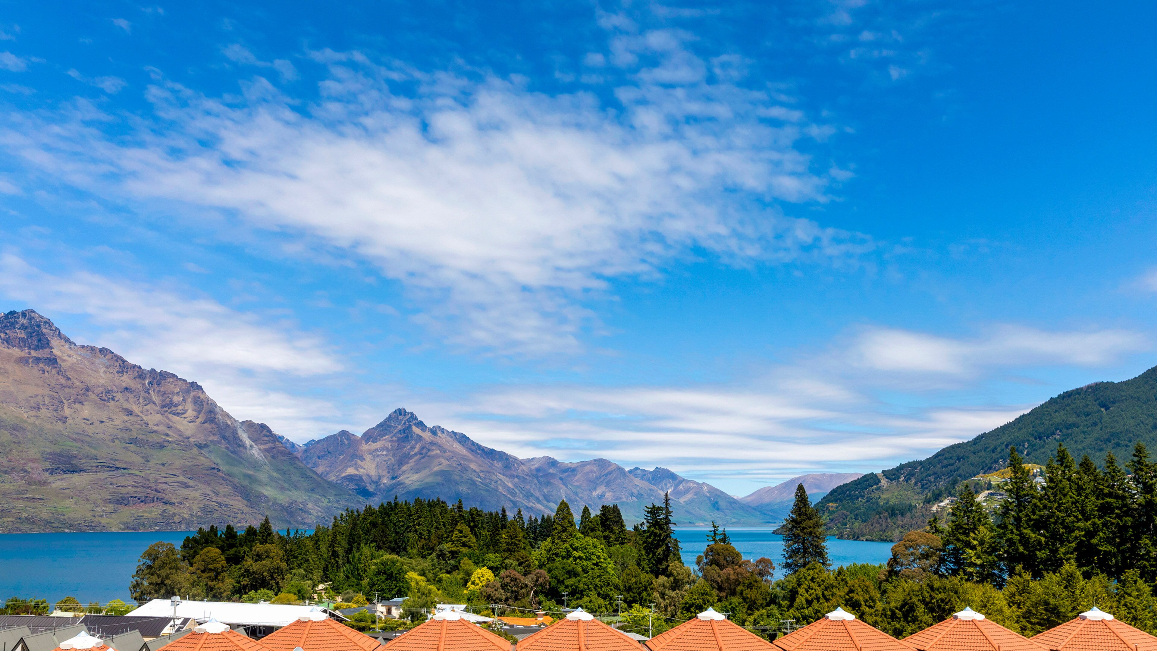 A mountainous landscape with a lake, forested area, and red-roofed buildings.
