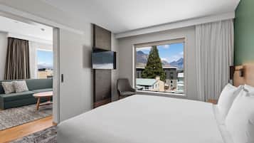 A hotel room with a bed, a sofa, a TV, and a window with a mountain view.