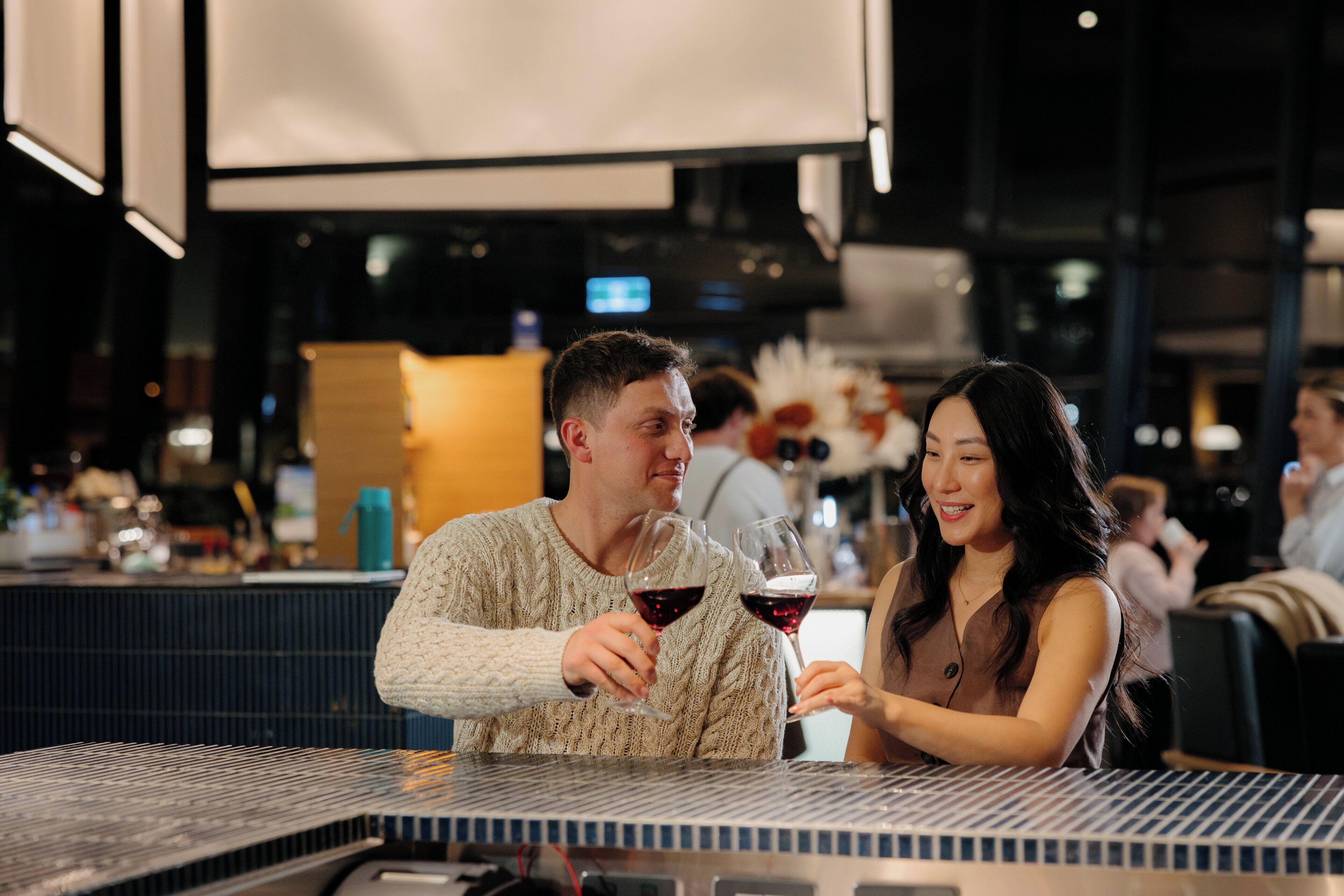 A couple seated at a bar with a piano keyboard in the foreground.