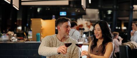 A couple seated at a bar with a piano keyboard in the foreground.