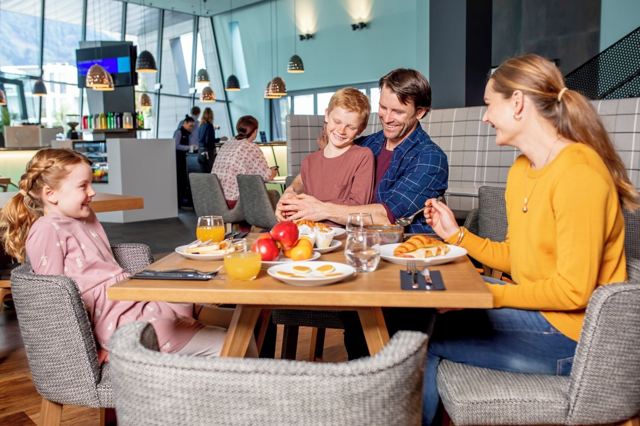 A family dining at a restaurant with a modern interior, including a high ceiling and pendant lighting.