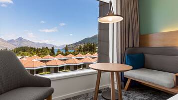 A hotel room with a view of mountains, a sofa, a chair, and a small table.