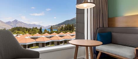 A hotel room with a view of mountains, a sofa, a chair, and a small table.