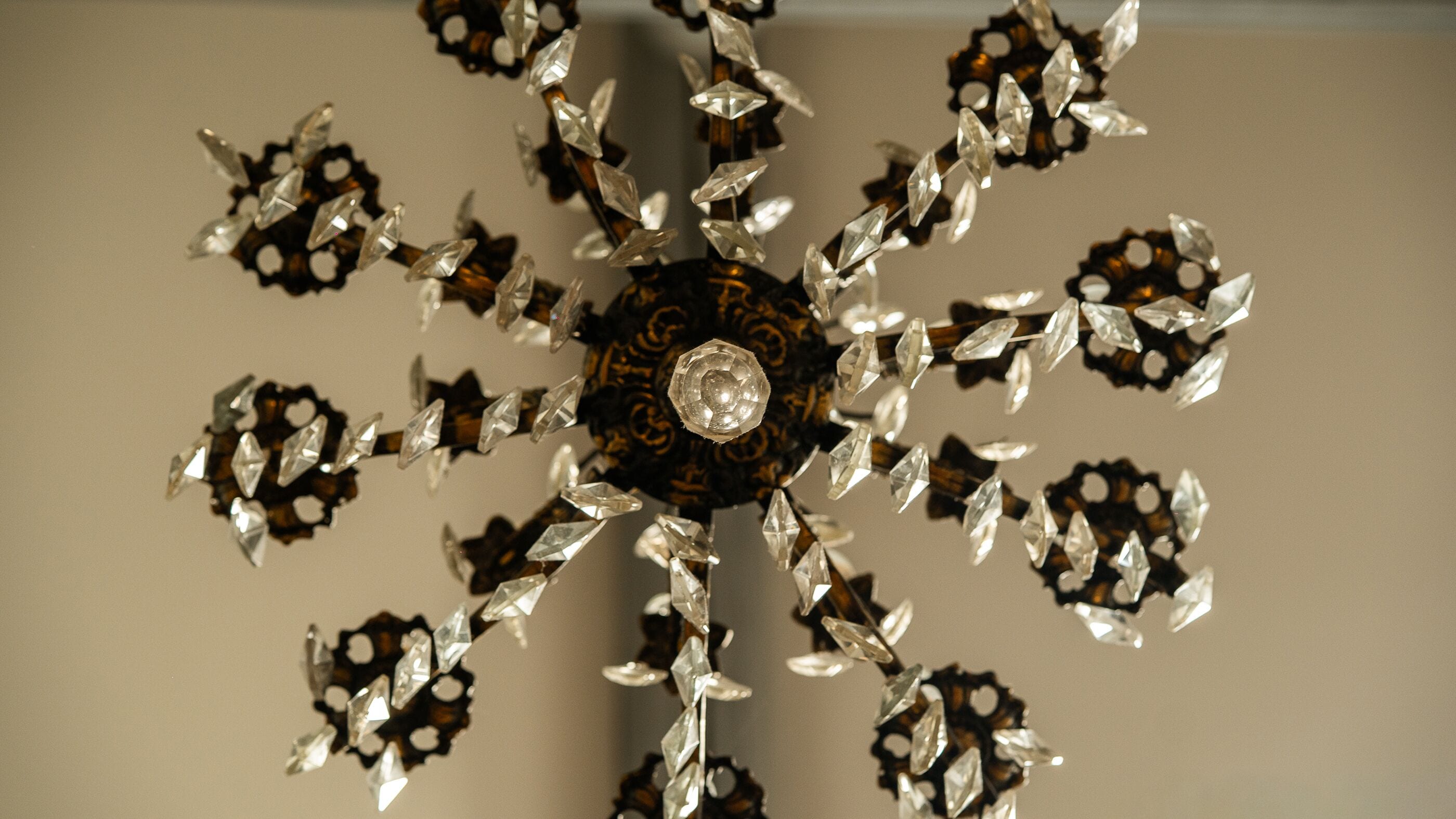 A chandelier with a central decorative piece and multiple arms adorned with crystal-like elements.