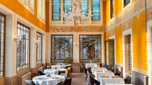 A dining area with round tables, chandeliers, and large windows with stained glass. - Manoir le Roure (Chateauneuf-du-Rhone)