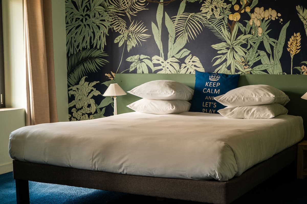 A bed with white bedding, two bedside lamps, and a pillow with a motivational quote.