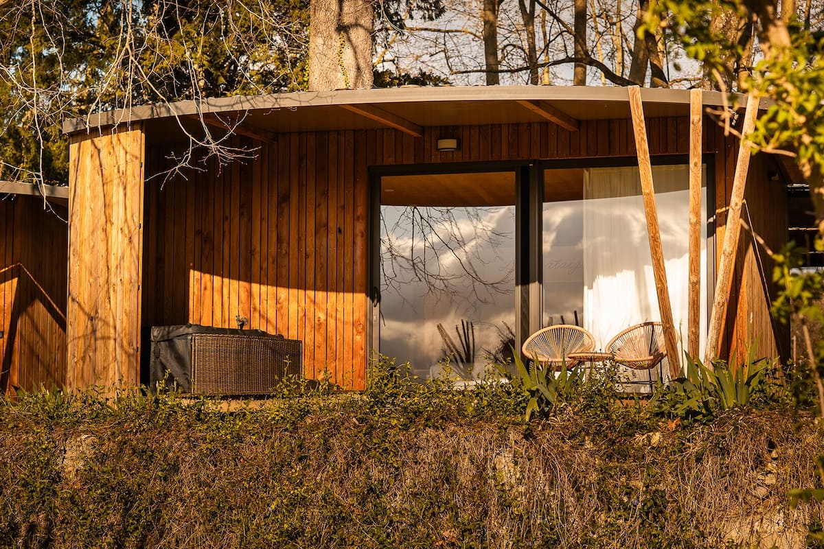 A wooden cabin with a large sliding glass door, wicker furniture, and a basket.