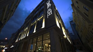Een modern gebouw met verlichte reclameborden, grote ramen en een glazen gevel.