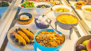 A buffet with various food items including fruits, salads, and cereals.