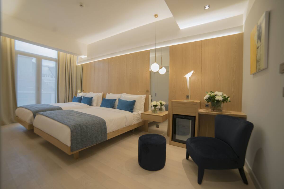 Una habitación de hotel moderna con una cama grande, un escritorio, una silla y una pequeña mesa con un florero.
