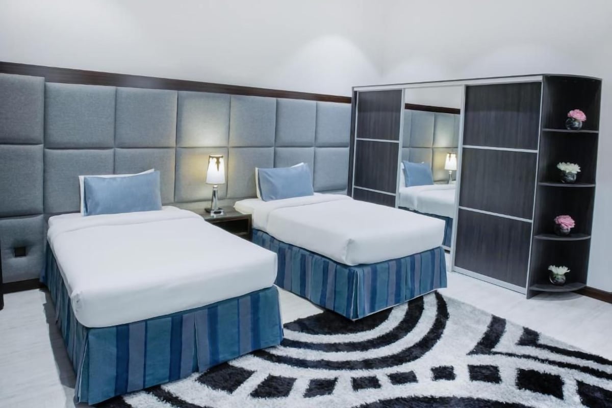 A hotel room with two beds, a large mirror, and a wardrobe.