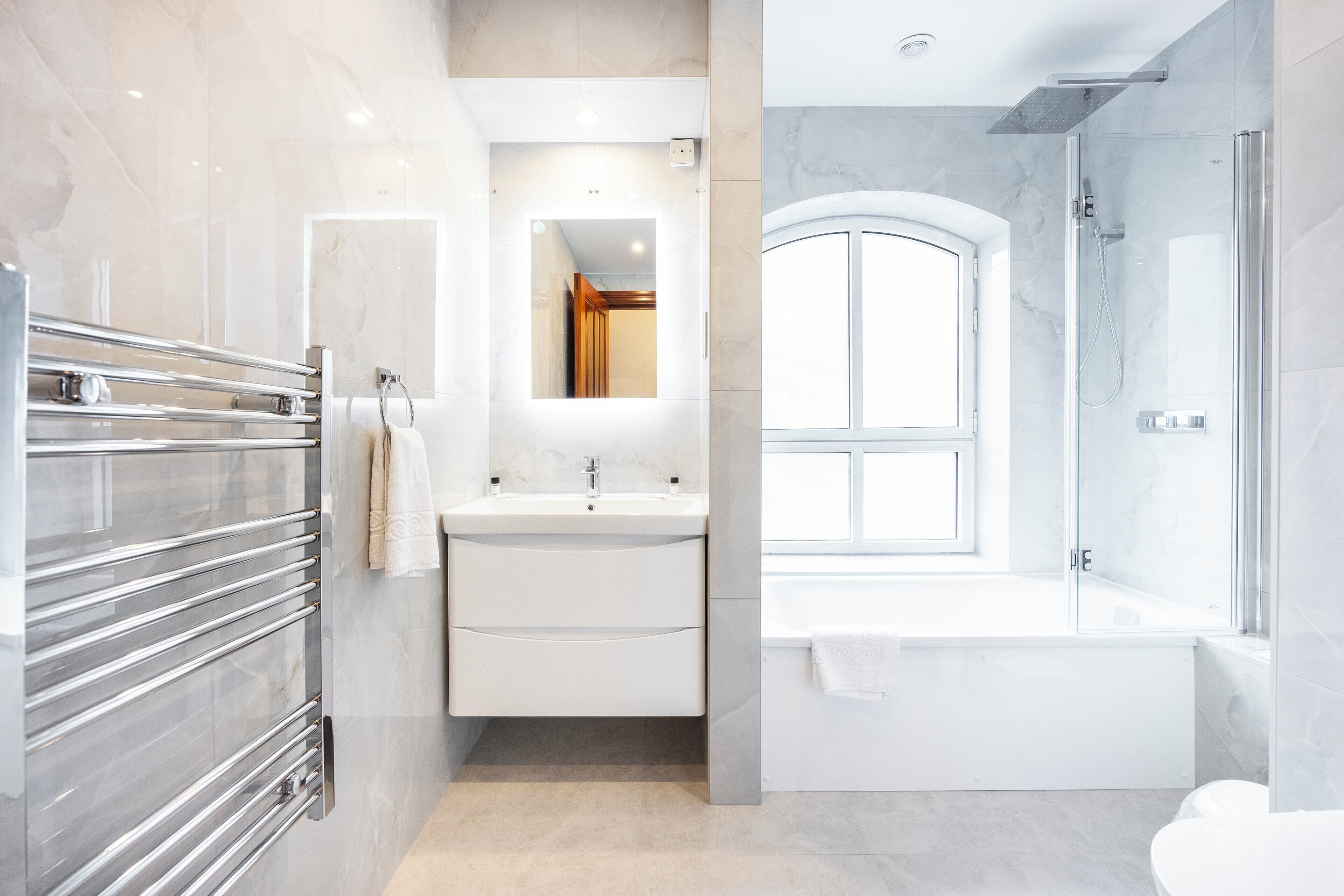 A modern bathroom with a glass shower enclosure, a freestanding bathtub, and a vanity with a mirror.