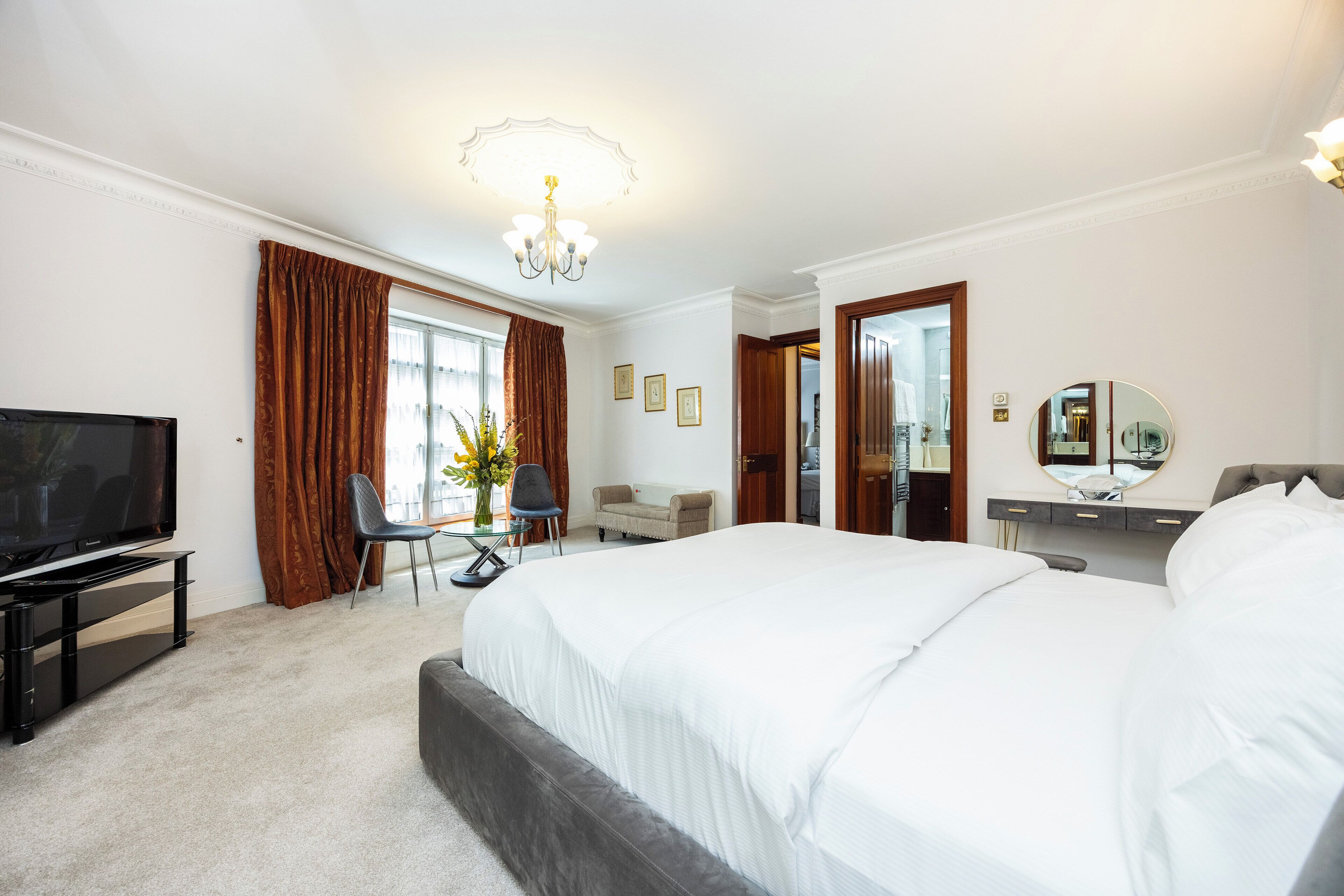 Habitación de hotel con una cama grande, televisión, escritorio y silla.