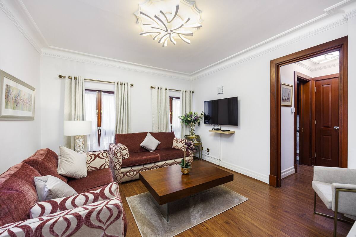 A living room with a sofa, a coffee table, a TV, and a door leading to another room.