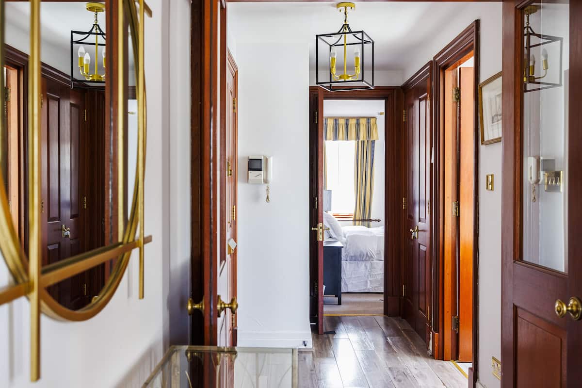 A hallway with wooden doors, a marble floor, and a bed in the background.