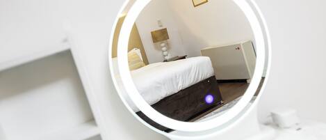 A modern bedroom with a bed, a bedside table, a lamp, and a wall-mounted radiator.