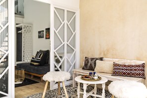 A modern living room with a sofa, a small round table, and a white pouf. - Suite Azur Hotel (Essaouira)