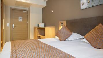 Una habitación de hotel con una cama bien hecha, un armario de madera y una estantería en la pared.