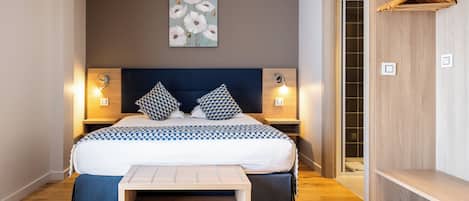 A bedroom with a bed, bedside tables, a bench, a wooden wardrobe, and a wall-mounted artwork.