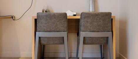 Un bureau avec deux chaises grises, un vase contenant des fleurs séchées et une lampe.
