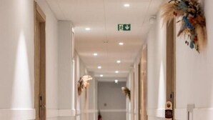 A long, narrow hallway with white walls and doors on both sides, leading to a room at the end. - Hôtel Le Bastia (Bastia)